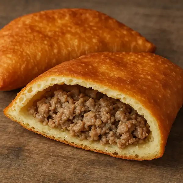 The photo shows a golden-brown fried pastry cut in half, exposing a savoury meat filling