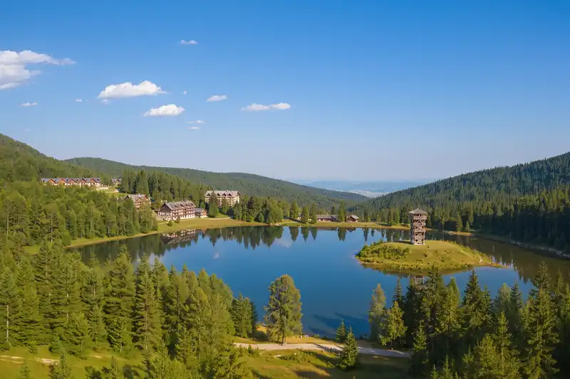 Forested hills, lookout tower and lake at Matrafured in the Mátra mountains.